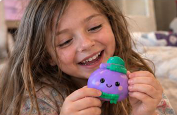 Girl smiling while squeezing a purple squishy dumpling